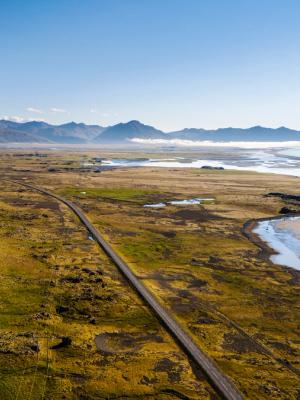 an aerial view of a road going through a valley with mountains in the background .