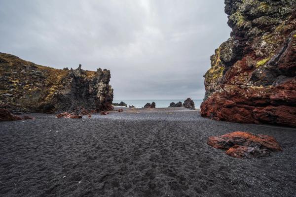 playa de arena negra con grandes rocas a los lados