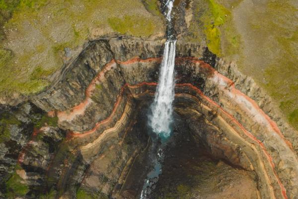 an aerial view of a waterfall in the middle of a canyon .