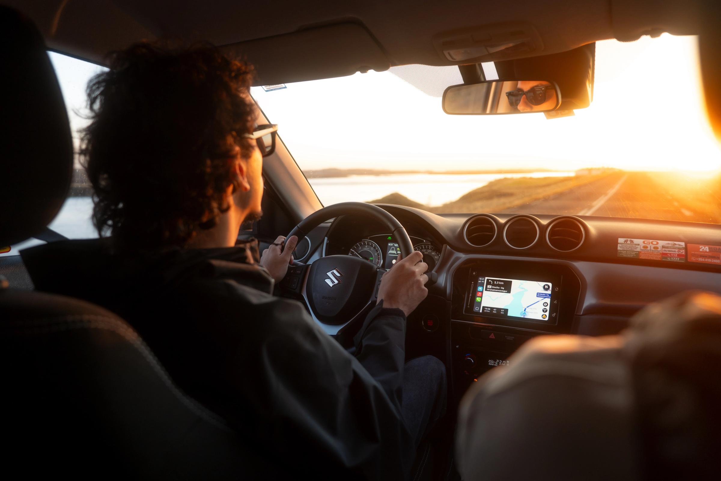 Vue intérieure d’un Suzuki Vitara avec le conducteur au volant et l’écran de navigation allumé