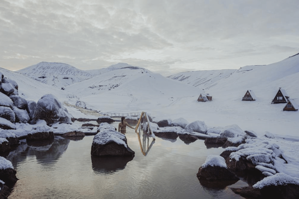 a snowy landscape with a bridge over a body of water at kerlingarfjöll in iceland.