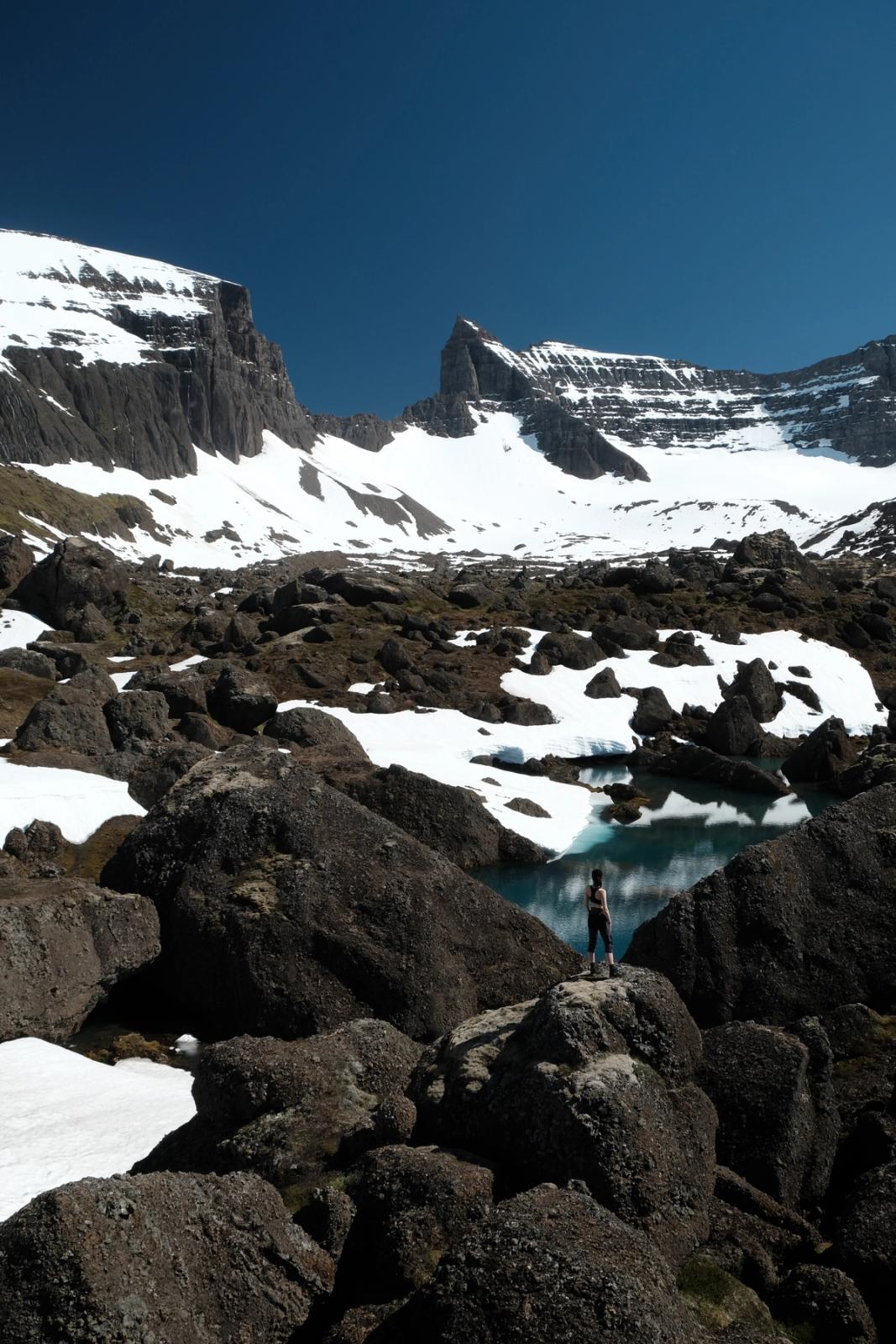 una persona de pie sobre una roca cerca de un lago en las montañas