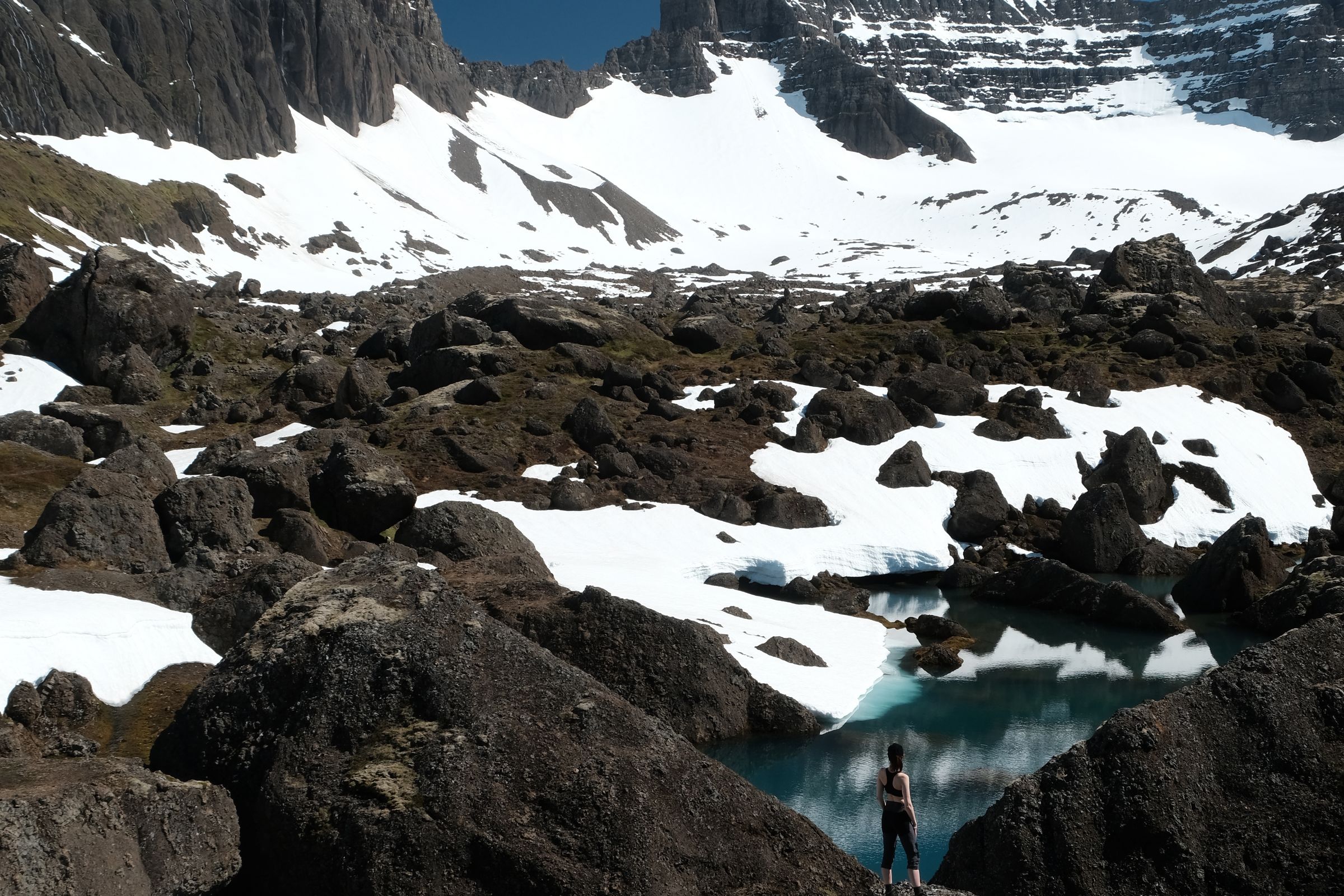 una persona de pie sobre una roca cerca de un lago en las montañas