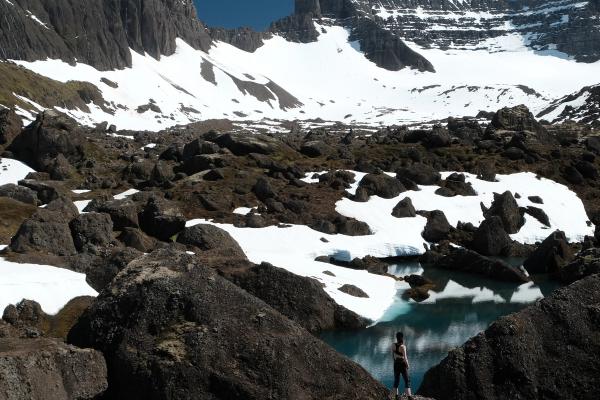 una persona de pie sobre una roca cerca de un lago en las montañas