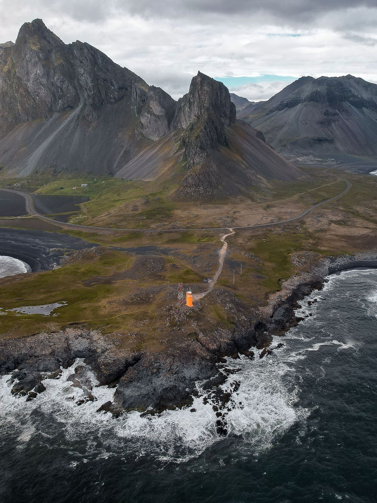una vista aérea de una pequeña isla en medio del océano con montañas en el fondo .