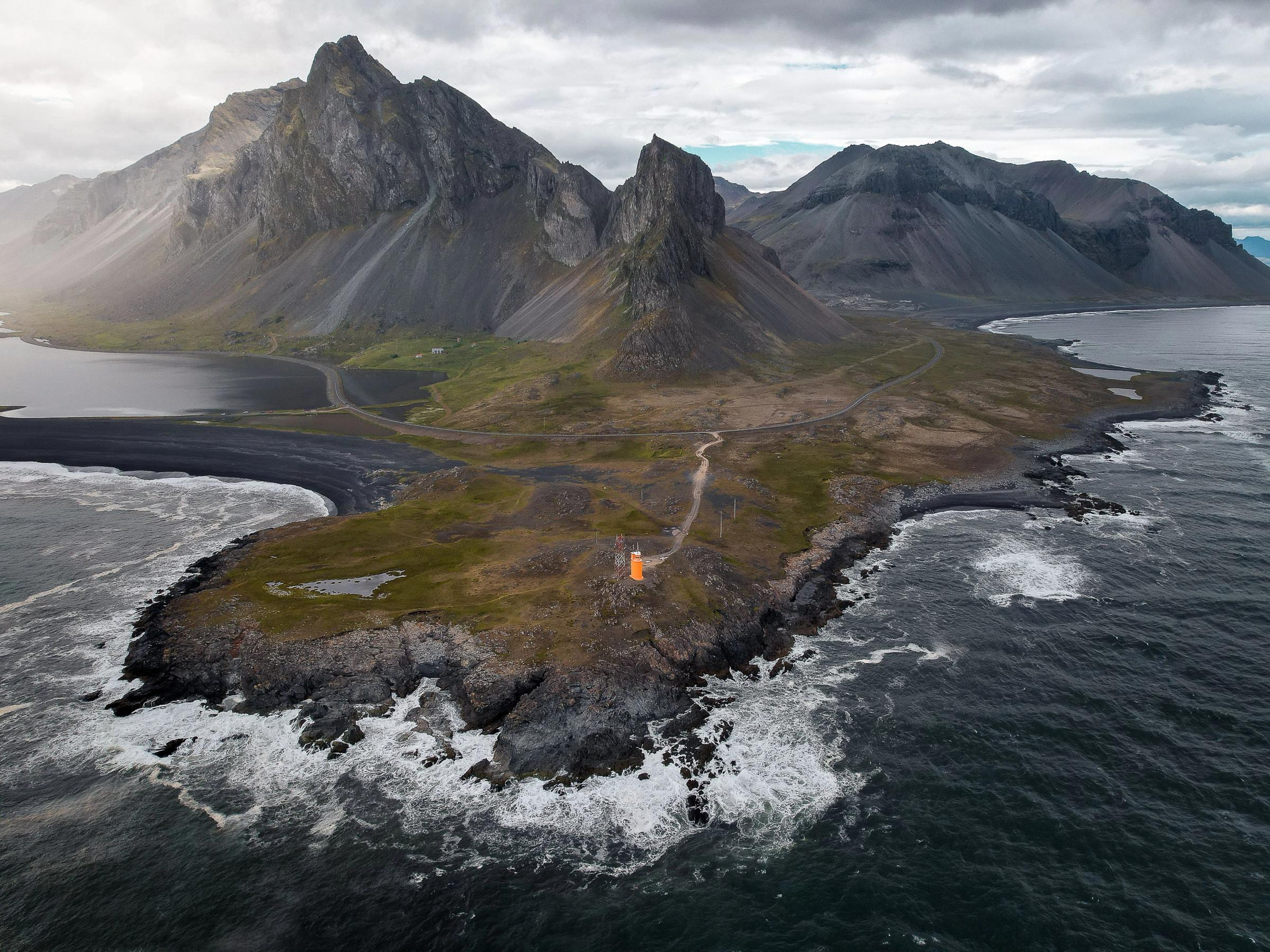 una vista aérea de una pequeña isla en medio del océano con montañas en el fondo.