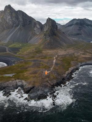 an aerial view of a small island in the middle of the ocean with mountains in the background .