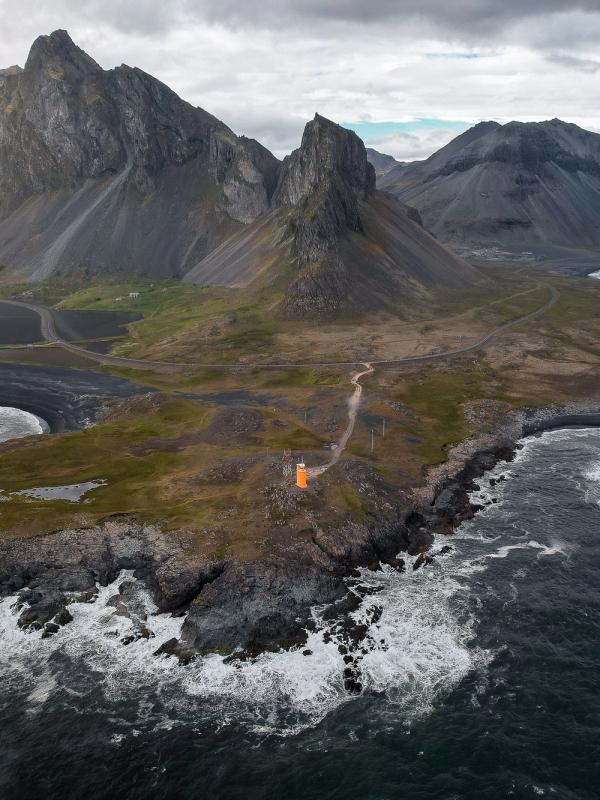 an aerial view of a small island in the middle of the ocean with mountains in the background .