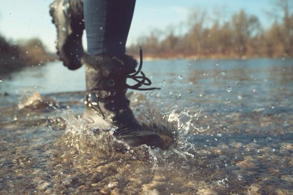 a person wearing snow boots is walking through a river .