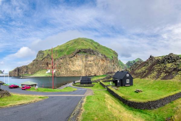 a panoramic view of a small village with a lake and mountains in the background .
