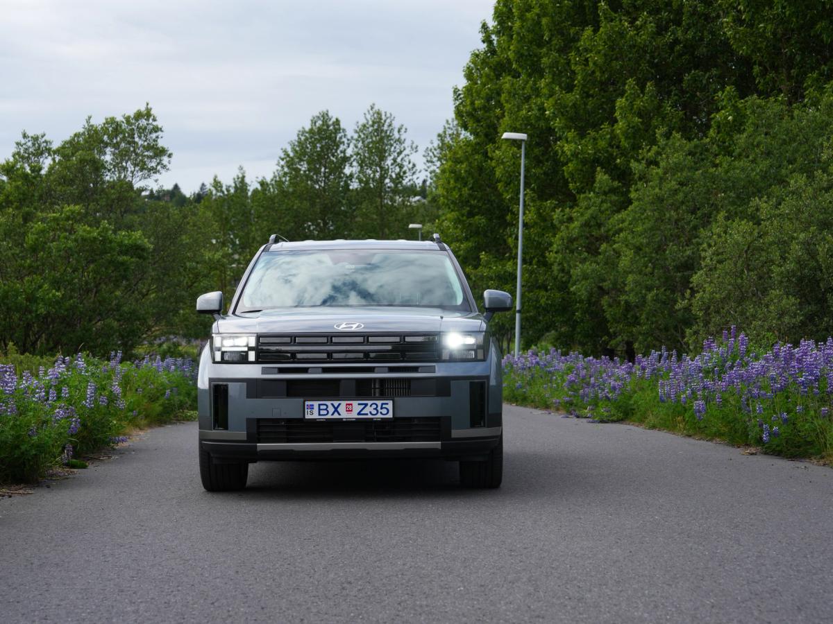 Santa Fe að framan Hyundai Santa Fe séður framan frá með kveikt aðalljós á mjóum malbikuðum vegi með lúpínum beggja vegna