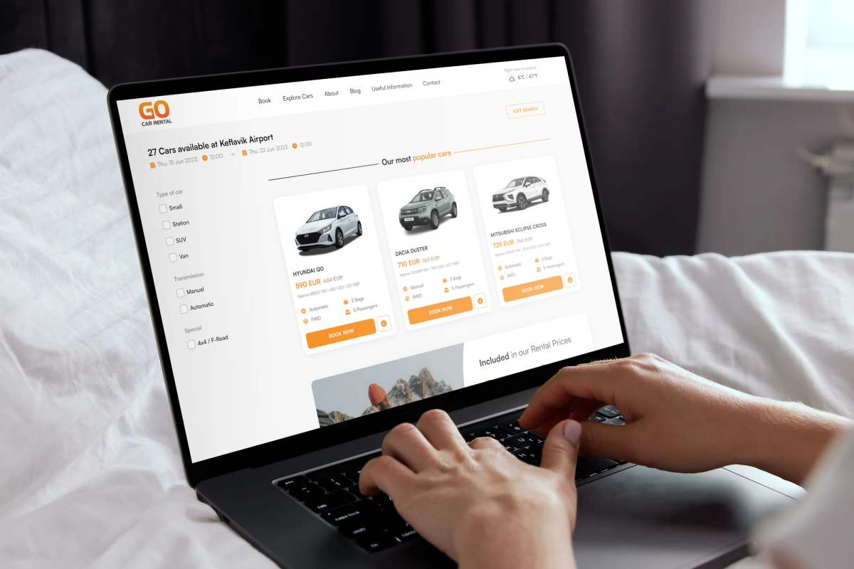 Hands typing on a laptop displaying a car rental website.