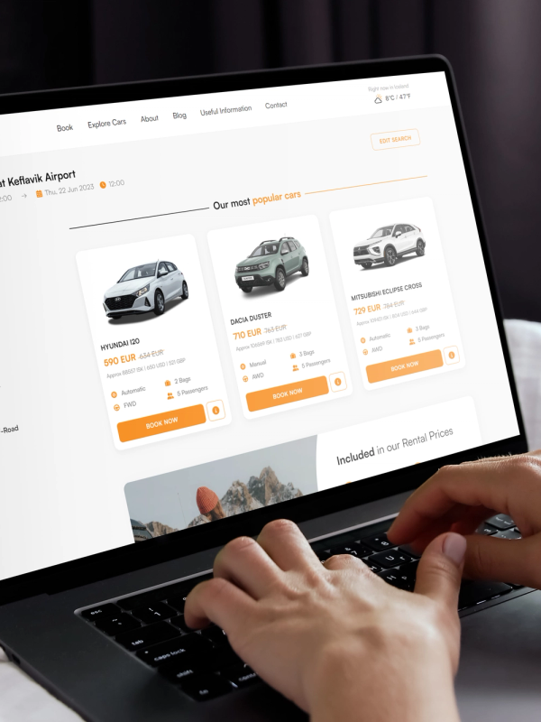 Hands typing on a laptop displaying a car rental website.