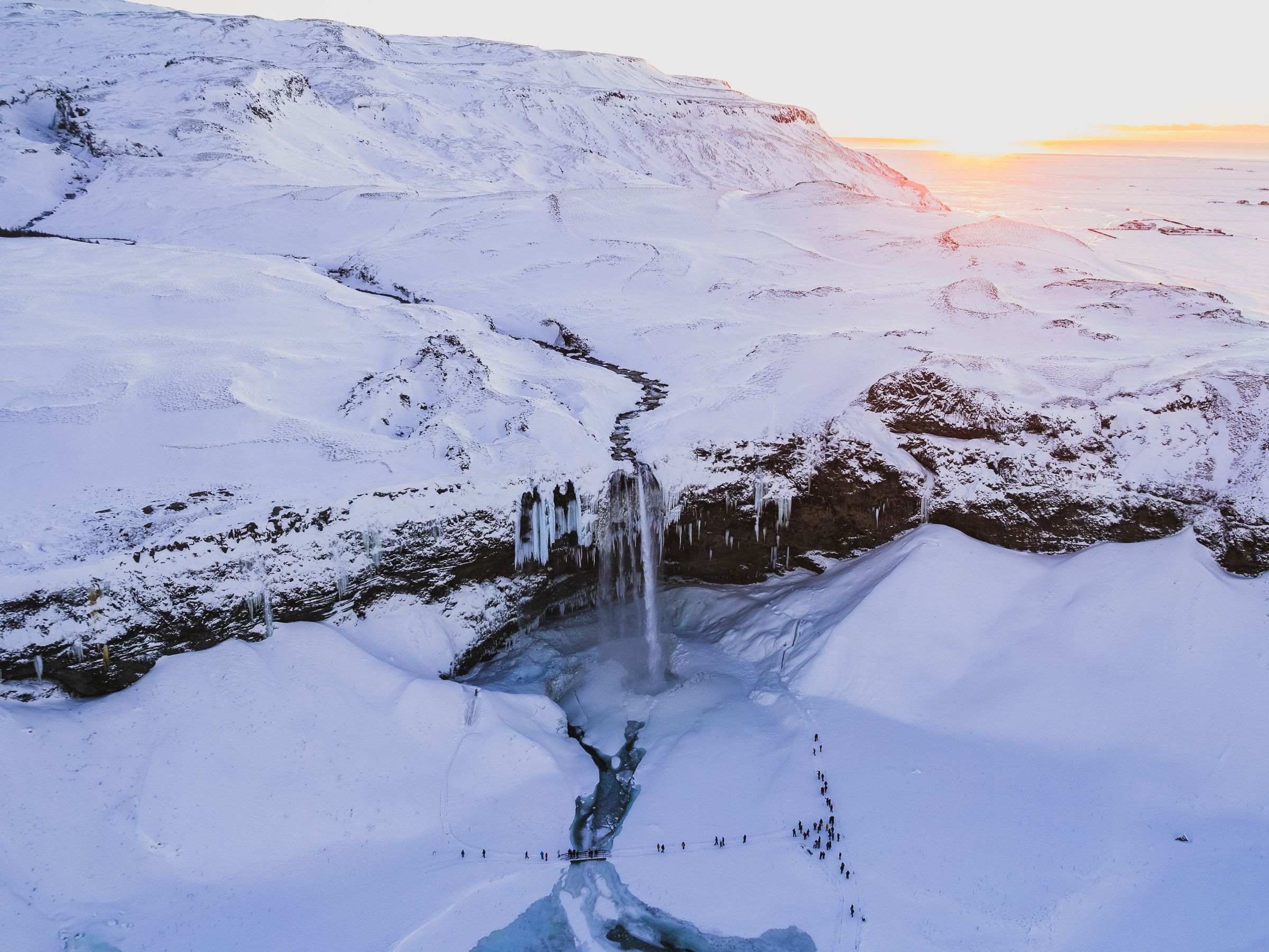 a waterfall during winter, surrounded by snow