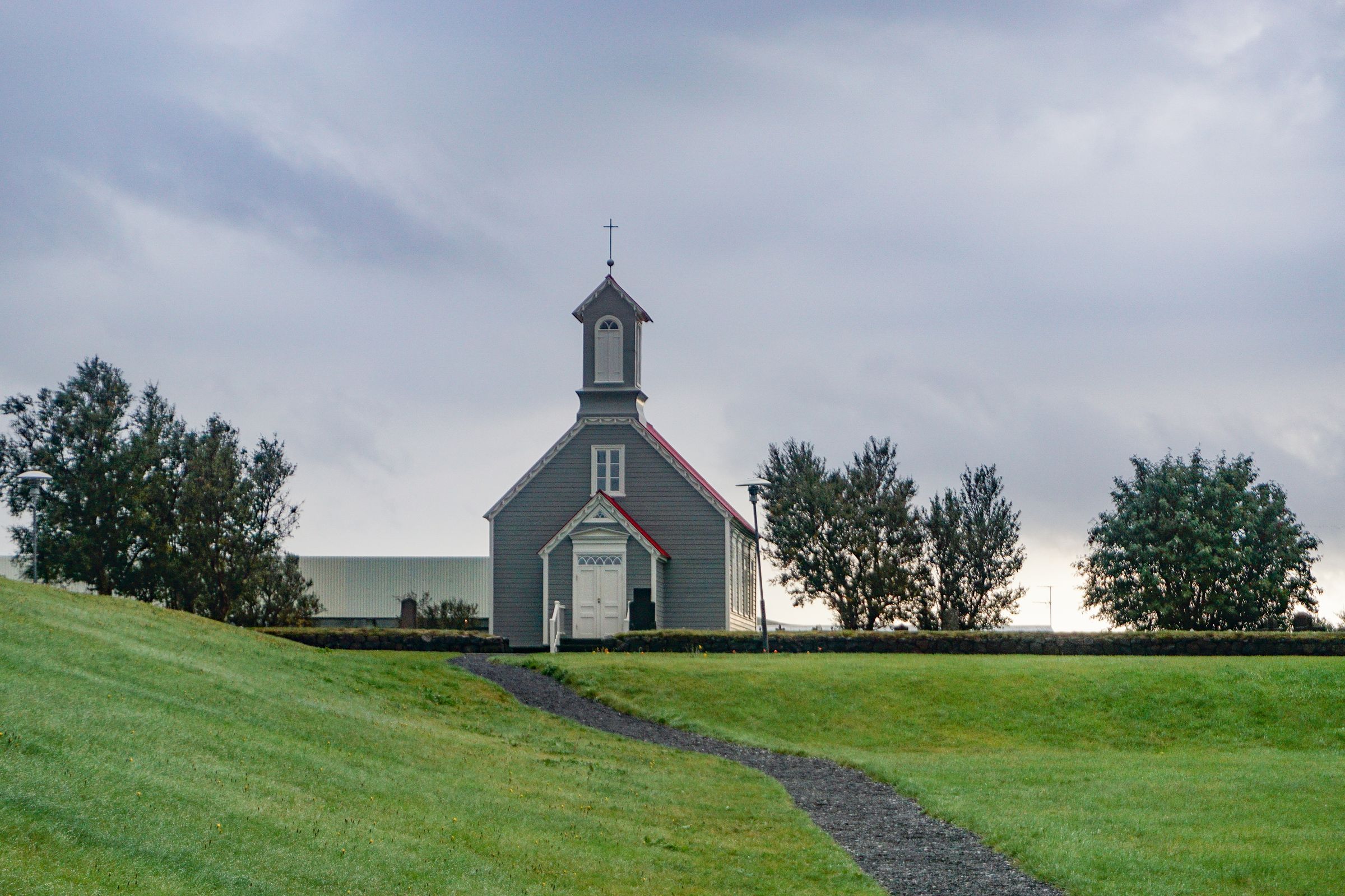 a small church with a red roof is sitting on top of a grassy hill at Snorrastofa in Reykholt Iceland.