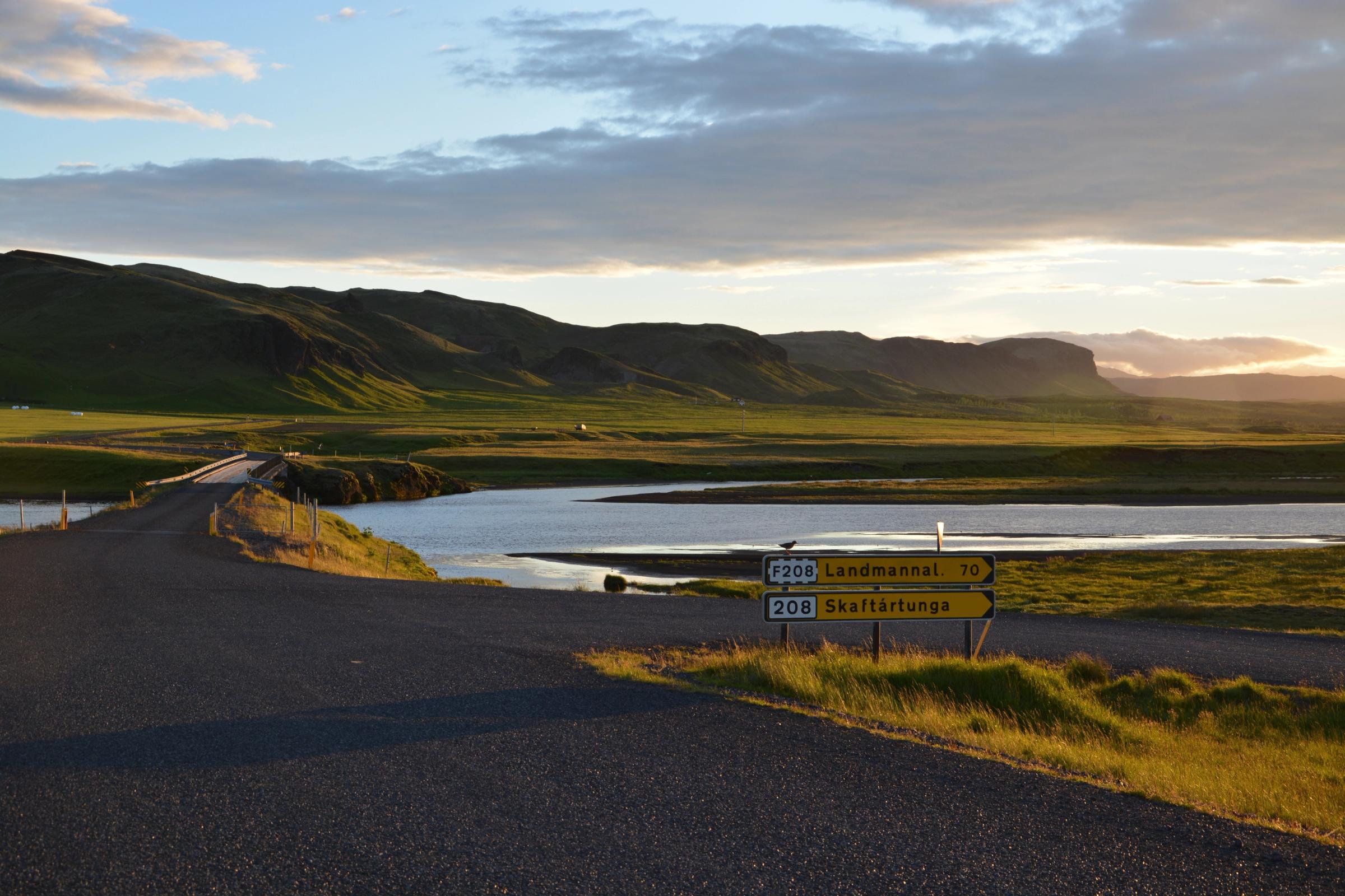 a road with a sign on the side of it and a river in the background .