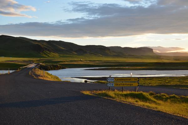 a road with a sign on the side of it and a river in the background .