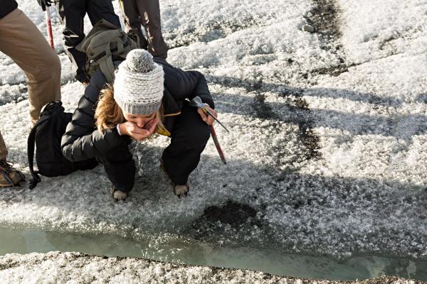 woman who makes a pause to drink during her hike on a glacier of Iceland