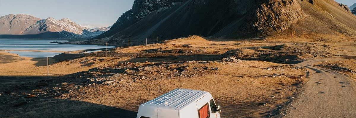 Una furgoneta blanca va por un camino de tierra en la montaña.