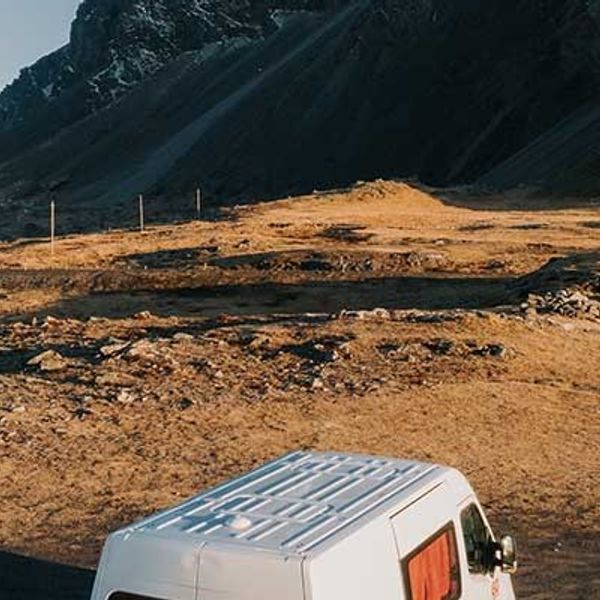 a white van is driving down a dirt road in the mountains .