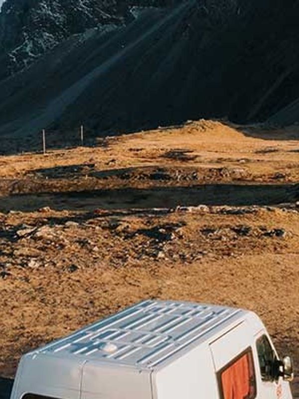 a white van is driving down a dirt road in the mountains .