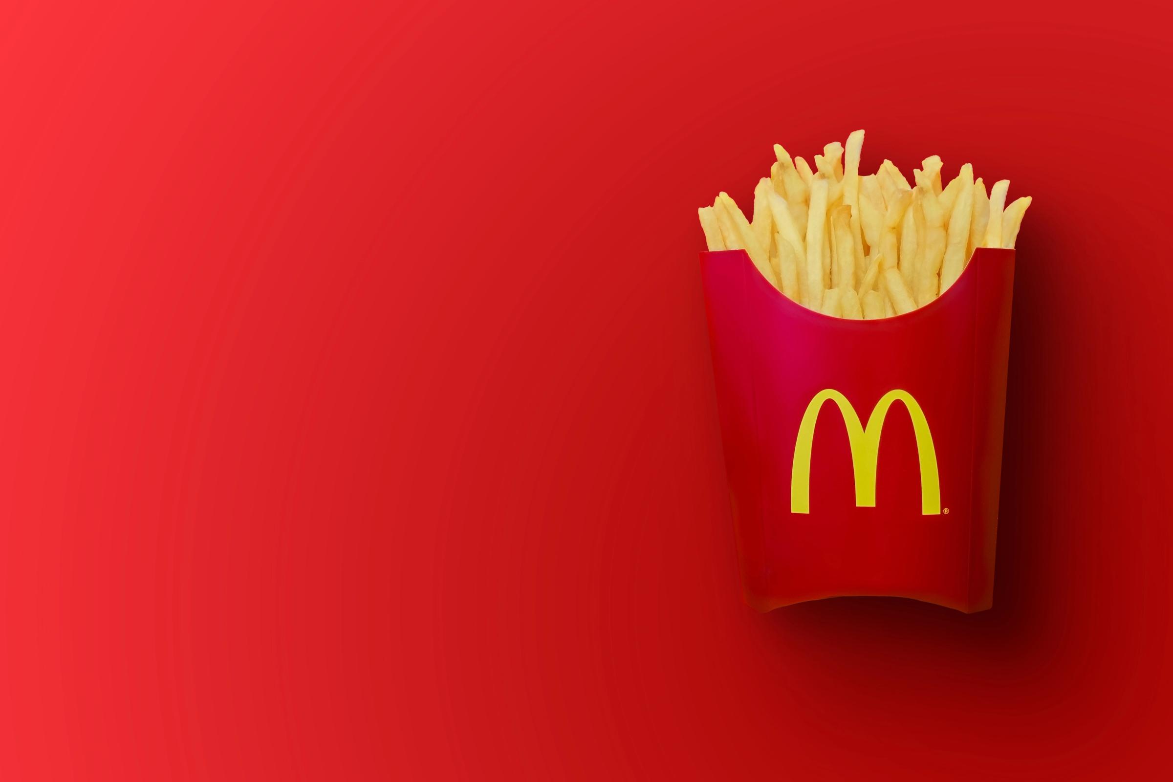 a bucket of mcdonald 's french fries on a red background .