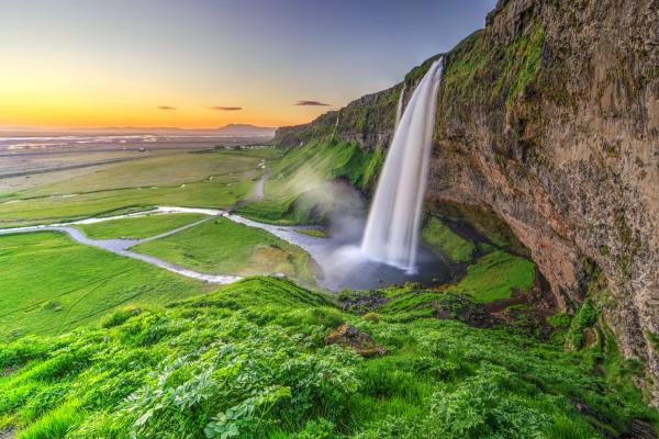 waterfall falling on a pond surrounded by green grass