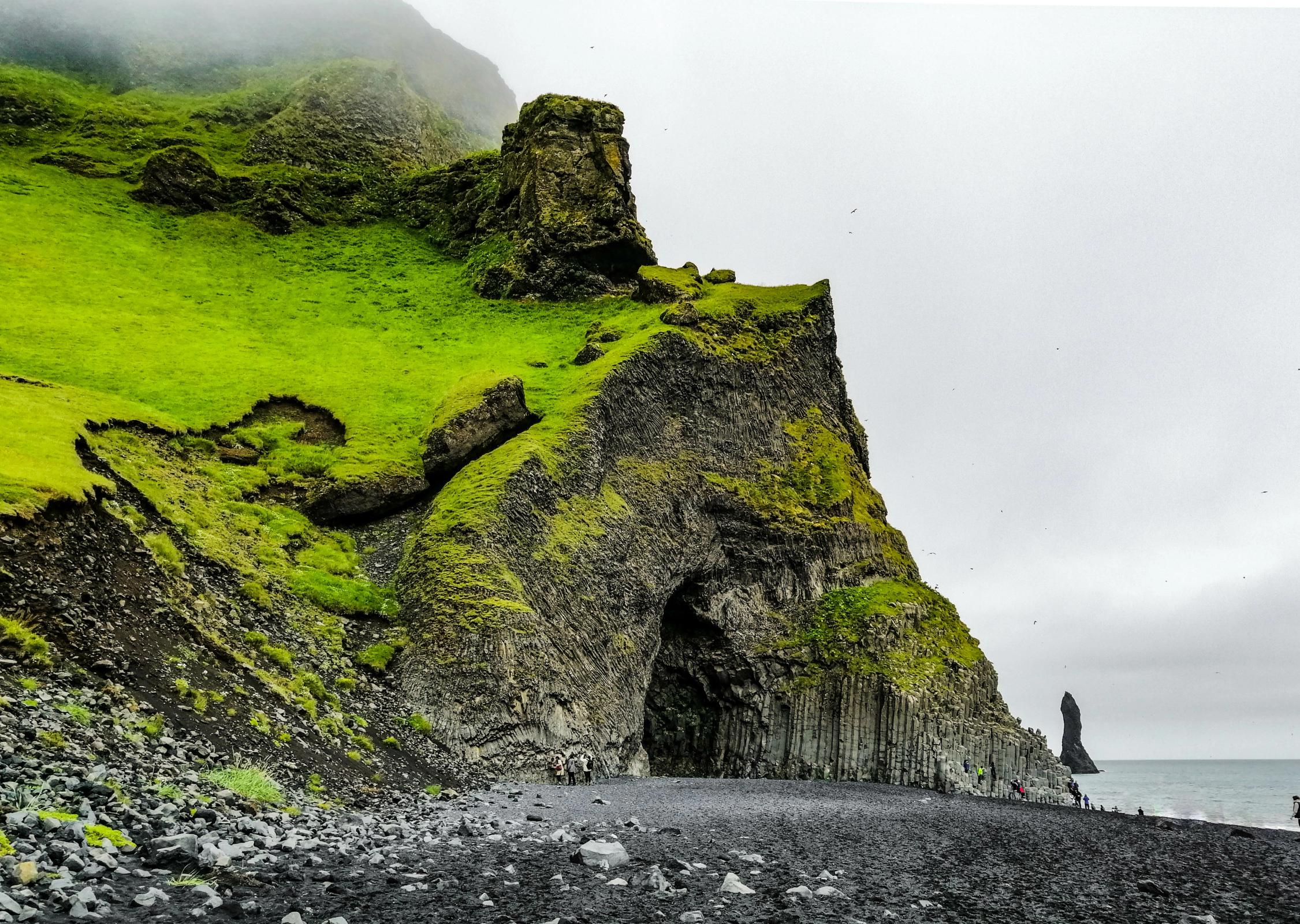 a cave under a cliff on a black sand beach