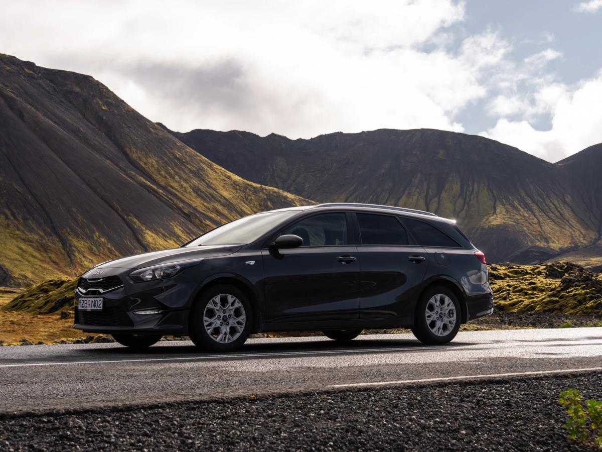 Ceed Wagon Paso de montaña Kia Ceed familiar de alquiler en Islandia, aparcado en una carretera asfaltada al pie de unas montañas cubiertas de musgo