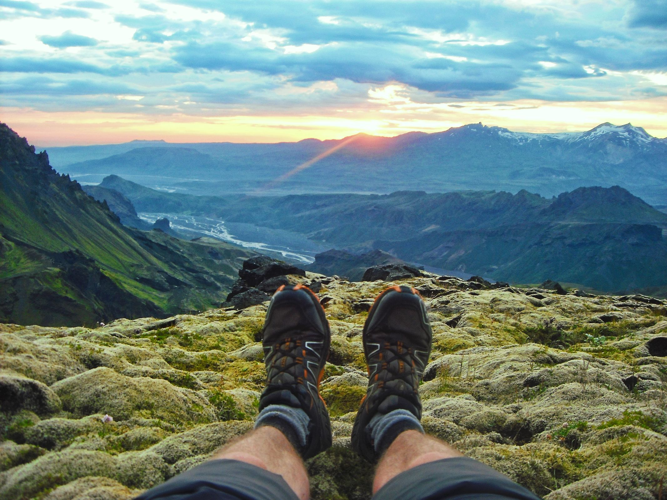 the legs and boots of a man with views of Thórsmörk valley on the background