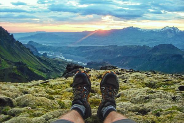 the legs and boots of a man with views of Thórsmörk valley on the background