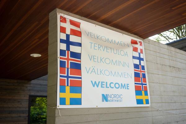 a welcome sign with flags on it is hanging on a wall .