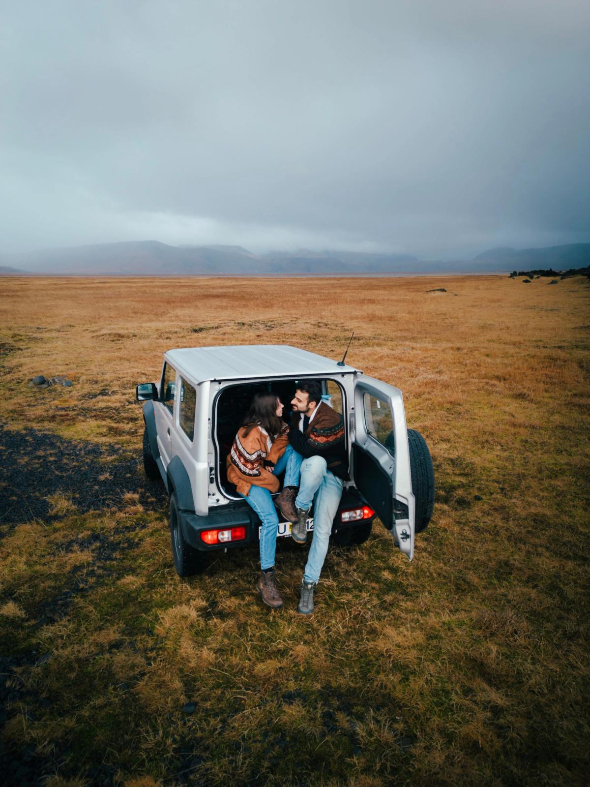 Una pareja sentada en la parte de atrás de un 4x4 blanco en medio de un campo