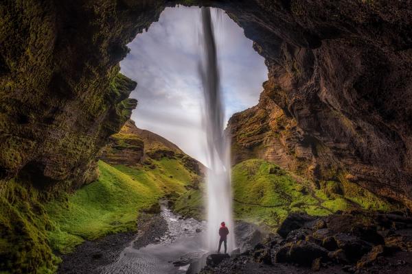 a man standing behind a thin waterfall