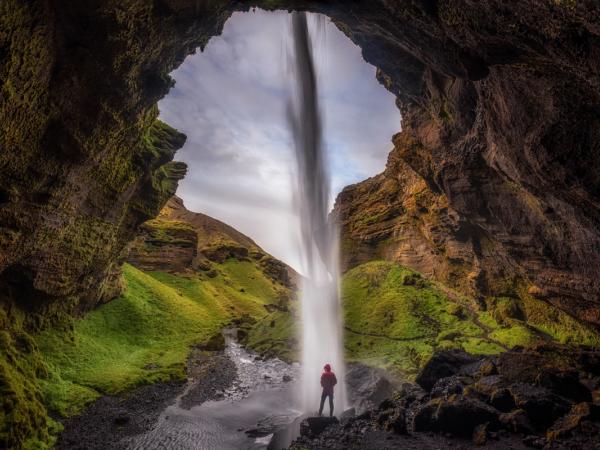 Man standing behind a waterfall