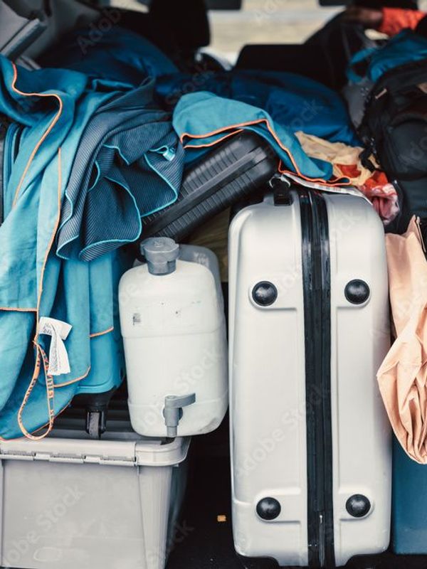 Trunk of car full of suitcases and clothes