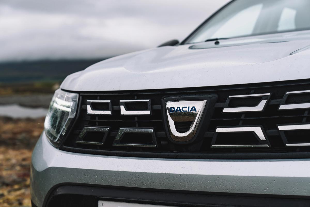 Dacia Duster close up of front grille and Dacia badge with coastline in background