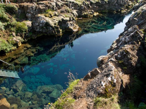 un barco está flotando sobre un gran cuerpo de agua rodeado de rocas .