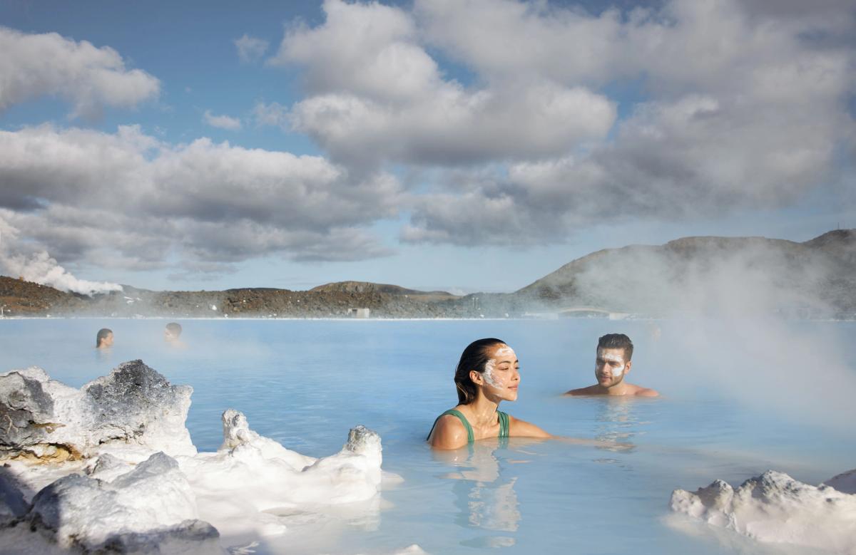 Man and a woman with a face max in blue lagoon hot spring in Iceland
