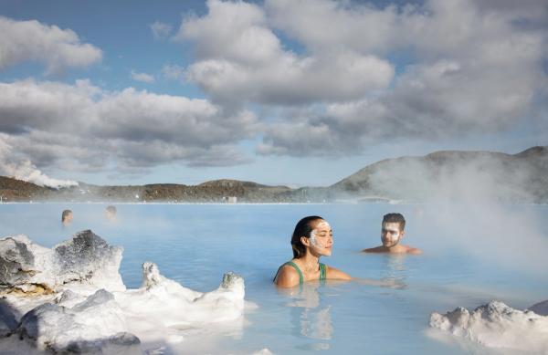 Man and a woman with a face max in blue lagoon hot spring in Iceland