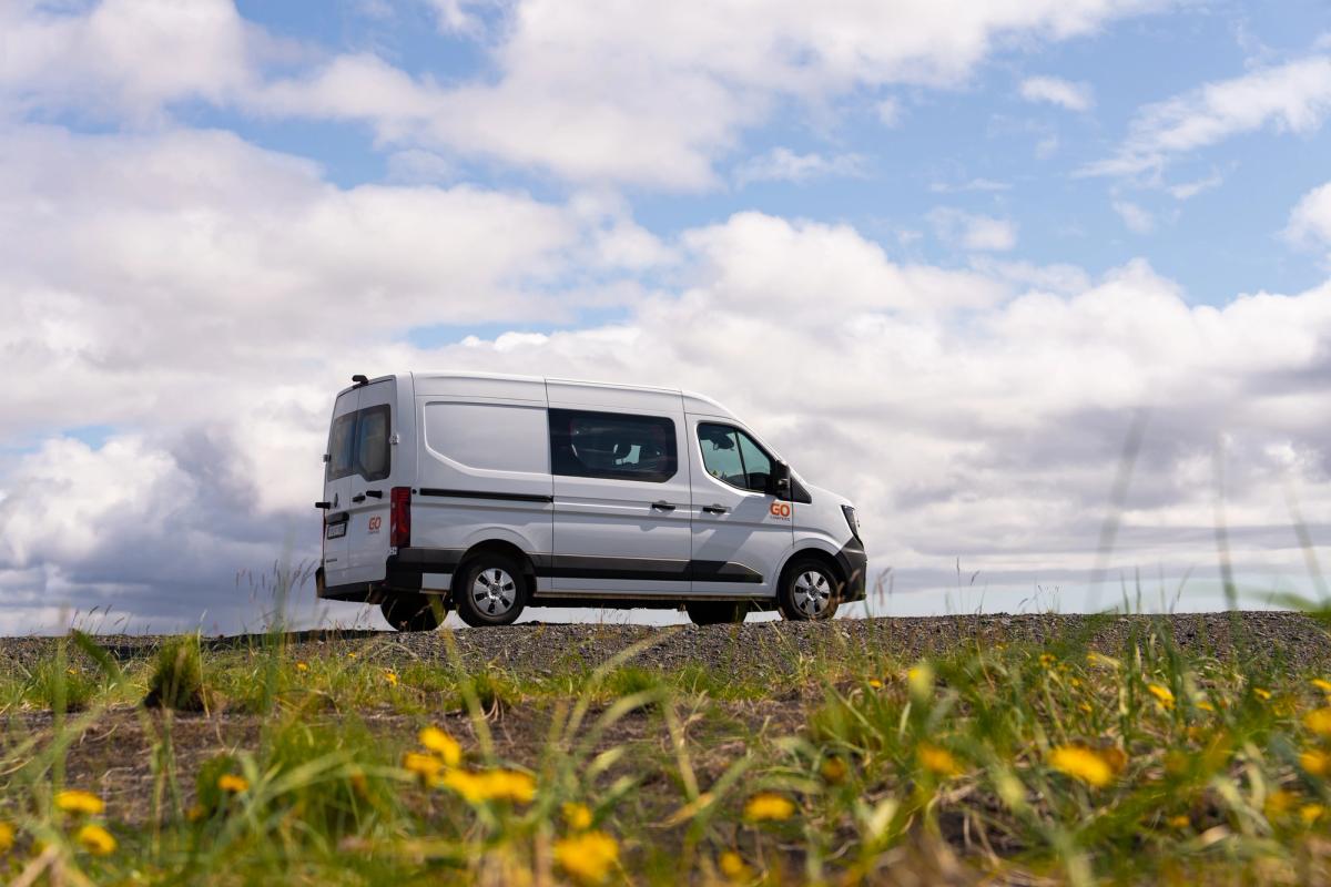 A 5 person large camper side on along a gravel road, seen from a low angle