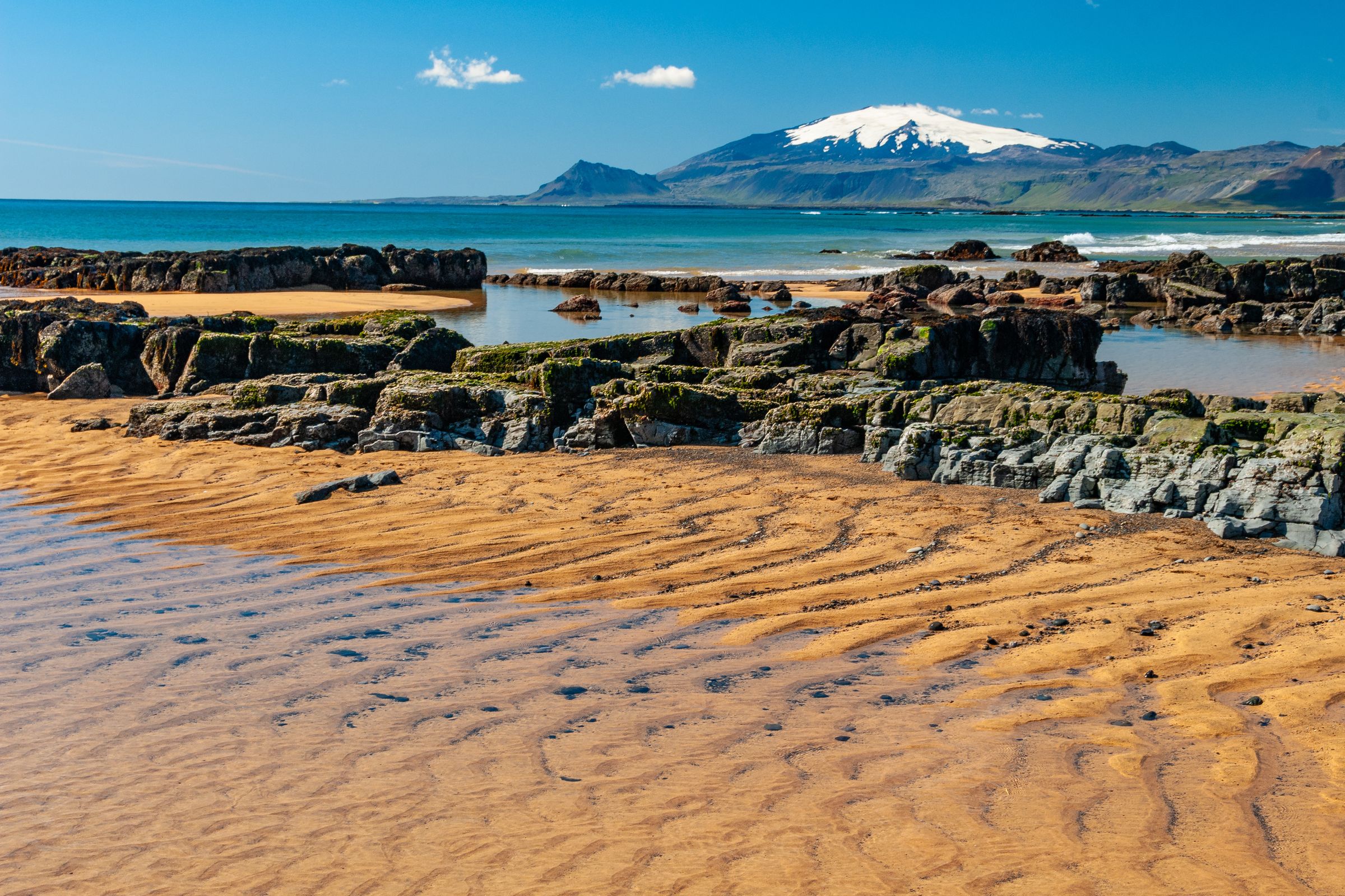 a sandy beach with rocks and a mountain in the background, Snæfellsnes Peninsula
