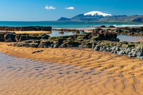 a sandy beach with rocks and a mountain in the background, Snæfellsnes Peninsula