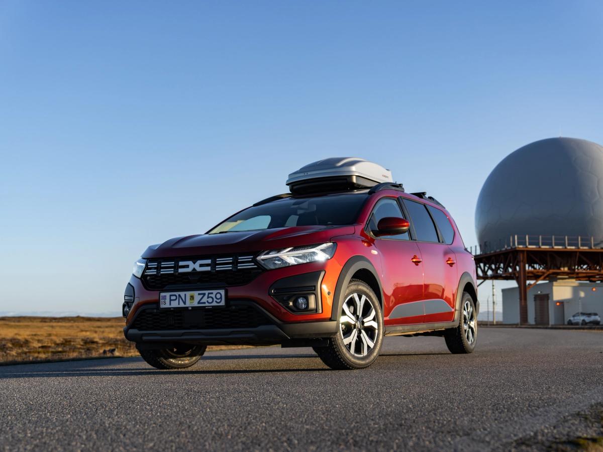 Jogginghose – Vorderansicht Dacia Jogger als Roadtrip-Fahrzeug in Island mit Dachbox, geparkt auf einer asphaltierten Straße