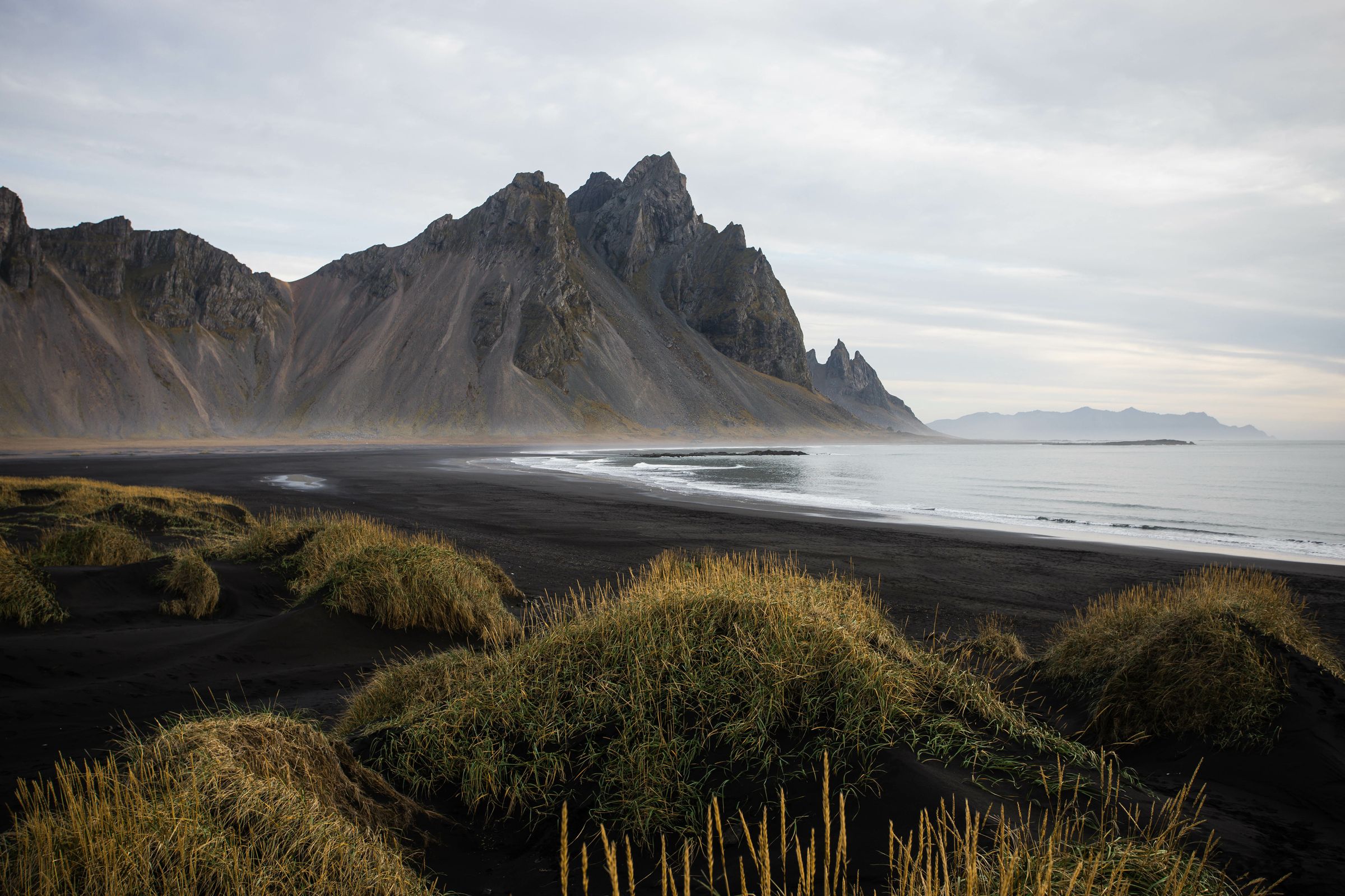 Plage de sable noir avec des montagnes en arrière-plan