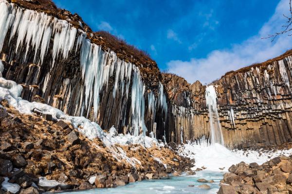 Partially-frozen waterfall flanked by basalt columns