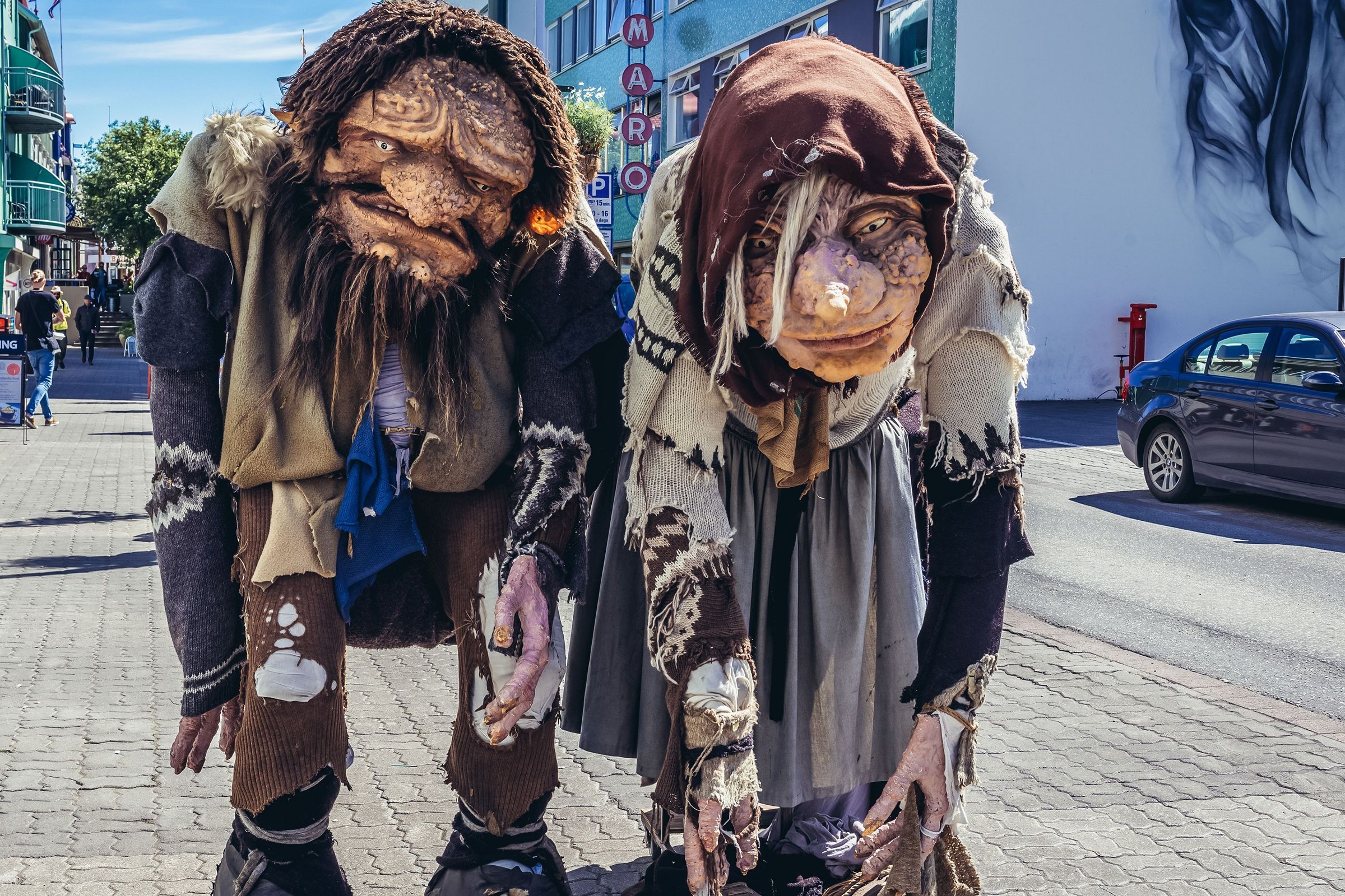 a man and a woman dressed as trolls are standing next to each other on a sidewalk .