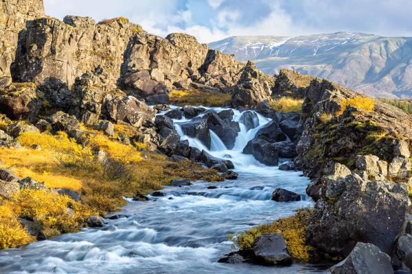 a river flowing through a rocky landscape with mountains in the background .