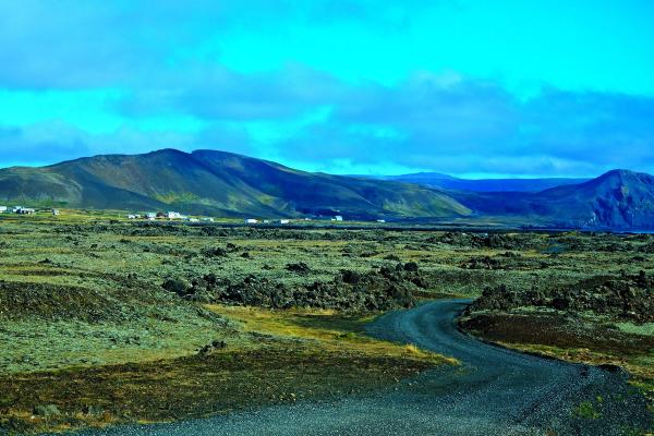 a dirt road going through a desert landscape with mountains in the background .