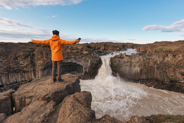 Man standing in front of Aldeyjarfoss Waterfall with his arms open